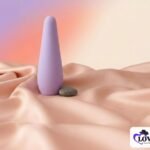 Soft lilac smooth wellness massager beside a stone on peach satin